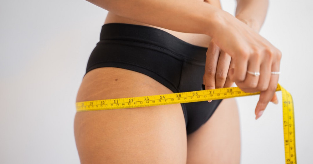 Woman using measuring tape to monitor weight loss